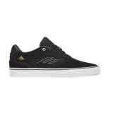 Championes de skate Emerica modelo The Low Vulc, color negro con detalles en dorado. Presentan una construcción de gamuza y lona, con suela vulcanizada blanca y logo de la marca en el lateral y talón.