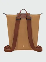 Mochila de diseño minimalista en color beige, con solapa y asa superior en cuero marrón texturizado. Cuenta con correas ajustables en color marrón y cierre principal.