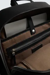 Mochila de diseño minimalista con acabado grabado, compartimento principal con cierre, espacio interior para dispositivos electrónicos de hasta 13 pulgadas, bolsillos frontales con cierre, parte posterior acolchada con banda de sujeción para equipaje, asa de mano y correas de hombro ajustables y acolchadas.