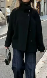 Chaqueta gris de paño con cuello alto y cierre frontal cruzado de doble botonadura.