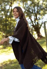 Ruana de lana merino color marrón, con diseño de tejido de punto texturizado y terminaciones con flecos en los bordes.