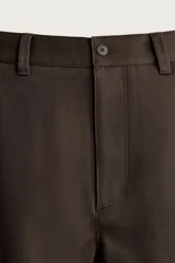 Pantalón chino de corte regular, color marrón oscuro, con cierre frontal de cremallera y botón, bolsillos laterales y bolsillos traseros de vivo.