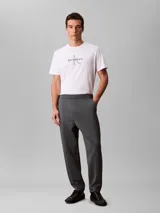 Pantalón de tejido grueso de punto liso con cintura elástica, corte ceñido y largo al tobillo. Presenta un diseño minimalista con logo de la marca bordado en el muslo.