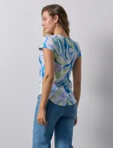 Remera color beige con estampado de hojas blancas, cuello redondo y mangas cortas.