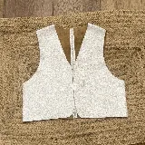 Chaleco de cuero de corte clásico y líneas limpias, con escote en V profundo y diseño sin cierre frontal. Presenta un acabado texturizado en tono plateado con interior en color marrón.