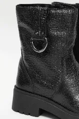 Bota de cuero negro con caña media, suela tractorada y detalle de hebilla metálica en el lateral superior.