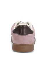 Championes de estilo urbano en color lila, confeccionados en material sintético con textura similar a la gamuza. Presentan detalles en color marrón oscuro en la puntera y el talón, cordones claros y suela de goma color caramelo.