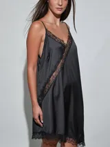 Vestido midi negro de satén con detalles de encaje en el escote, el ruedo y una aplicación diagonal que cruza el diseño. Cuenta con tirantes finos y un corte fluido.