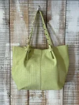 Cartera tipo shopper de cuero gris con textura símil cocodrilo, diseño amplio, correas ajustables con tachas y cierre superior.