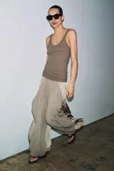 Pantalón bombacho de tiro medio en hilatura de viscosa color beige, con bolsillos laterales ocultos, volantes delanteros a tono, bajo abullonado con elástico y cierre lateral con cremallera oculta.