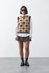 Chaleco tejido sin mangas con diseño de rombos tipo argyle en tonos marrón y beige, con cuello redondo y terminaciones acanaladas.