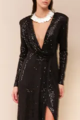 Vestido largo de lentejuelas color negro, con escote profundo en V, mangas largas y tajo lateral en la falda. Presenta un diseño cruzado con fruncido en la cintura y espalda elastizada.