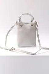 Bandolera plateada de cuero sintético con textura granulada, doble asa corta y correa larga regulable y extraíble.