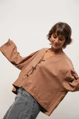 Blusa marrón de corte crop, escote en V y mangas largas anchas. Cierre frontal con lazos.