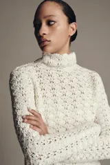 Jersey de punto con cuello subido y manga larga, confeccionado con un diseño de tejido combinado que presenta una textura calada y delicada.