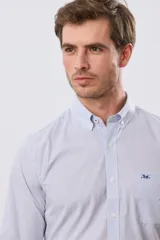 Camisa de manga larga con diseño de cuadros vichy en tono celeste y blanco, cuello abotonado y bolsillo frontal en el pecho con logo bordado.