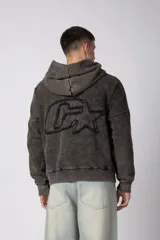 Buzo canguro de corte oversize en color gris con efecto lavado desgastado. Presenta diseño con recortes horizontales, capucha amplia y puños acanalados con etiqueta de marca en la manga.