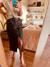 Pollera midi de cuero negro con abertura frontal y costuras blancas a contraste.