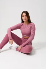 Conjunto deportivo de tres piezas en color rosa viejo, compuesto por un top de bretel ancho, un top de manga larga y una calza chupín. Las prendas presentan un diseño sin costuras con detalles de tejido texturizado y el logo de la marca estampado en blanco.