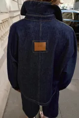 Cazadora de denim azul oscuro con cuello solapa, manga larga, cierre frontal con botones metálicos y bolsillos delanteros de plastrón.