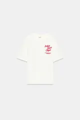 Camiseta de algodón color blanco hueso, corte regular, con cuello redondo y manga corta. Presenta un estampado pequeño en color rojo oscuro en el pecho con el texto "Action Heart Object" y detalles adicionales.