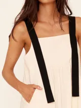 Vestido midi color crema con tirantes anchos negros, corte evasé y bolsillos laterales.