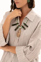 Camisa de textura plisada en color beige, con cuello clásico, cierre frontal de botones y mangas tres cuartos con puños vueltos.