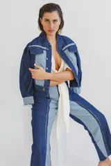 Jean de corte recto confeccionado en denim de algodón, con diseño bicolor que combina paneles en azul oscuro y azul claro. Presenta cierre frontal con cremallera y diseño de costuras verticales marcadas.