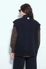 Chaleco de jean con corte oversized, diseño sin mangas, cuello camisero, cierre frontal con botones metálicos y bolsillos frontales tipo cargo.