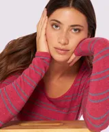 Remera de manga larga con cuello redondo, confeccionada en tejido rayado horizontal en tonos rojo y azul, con detalle de pin metálico con logo en la parte frontal.