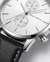 Reloj de pulsera analógico Mini Focus con caja de metal plateado, esfera blanca minimalista con subesferas y correa de cuero negro con costuras blancas.