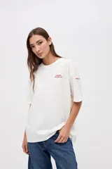 Remera de manga corta color azul, con calce clásico y tajos laterales. Presenta un bordado pequeño en el pecho con el texto 'UNIFORM STUDIO LAB' y un detalle bordado en la manga. Confeccionada en algodón lavado con textura suave.