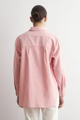 Camisa de corte oversized con estampado de rayas verticales, cuello clásico, cierre frontal con botones y bolsillo en el pecho.