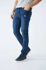 Pantalón de jean corte regular, color azul oscuro, con diseño de cinco bolsillos, pasacintos y detalles de roturas localizadas en la parte frontal.