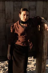 Camisa marrón con lunares blancos, corte clásico, cuello camisero, mangas 3/4 abullonadas y lazo ajustable en la cintura.