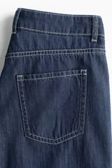 Jean de cinco bolsillos en denim rígido, de corte wide leg y tiro regular, con piernas amplias y costuras en contraste.