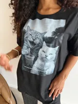 Remeron de algodón color marrón con estampa frontal de dos gatos bebiendo café. Presenta un corte oversize, cuello redondo y mangas cortas.