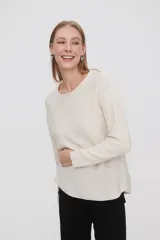 Sweater de punto color crudo, con cuello redondo y mangas largas.