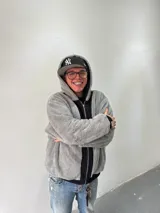 Campera reversible con cierre frontal, diseño oversize. Un lado es de algodón negro con estampados y bordados gráficos, mientras que el otro lado es de tela polar gris de pelo largo. Cuenta con capucha, puños y ruedo acanalados.