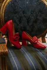 Zapato de cuero rojo con aplique decorativo en el empeine y tacón cuadrado.