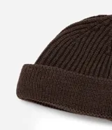 Gorro tipo fisherman de tejido acrílico con textura acanalada, diseño corto y etiqueta pequeña con logo en el frente.