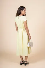 Vestido midi amarillo pálido, de corte recto y manga corta, con escote redondo con detalle de bordado floral. Tiene lazo ajustable en la cintura.