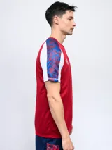Remera de fútbol Umbro del Club Nacional de Football, modelo Pro Training Active. Diseño con estampado abstracto en blanco, rojo y azul, con mangas raglán azul marino y escudo del club en el pecho.