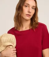 Vestido corto marrón oscuro, estilo camiseta, con escote redondo, mangas cortas y bolsillos laterales. El bajo es redondeado.