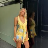 Vestido corto con escote en V profundo y volados frontales, de diseño ajustado con estampado floral y animal print en tonos amarillos y azules.