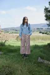 Camisa de denim celeste con cuello clásico, cierre frontal de botones y detalle de volados en los hombros.