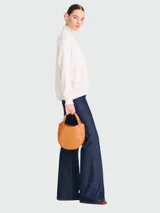 Cartera de mano Longchamp modelo Le Foulonné S, de diseño redondeado y estructura rígida, confeccionada en cuero con acabado liso y asa superior integrada.