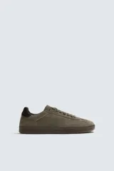 Zapatilla de estilo urbano confeccionada en piel con acabado de serraje en tono marrón. Presenta cierre de cordones al tono, detalle de pespuntes en el empeine y suela de goma a tono.