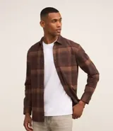 Camisa marrón a cuadros con cuello camisero, manga larga, bolsillo en el pecho y cierre abotonado.