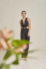 Enterito largo negro de diseño elegante, con escote en V profundo, sin mangas y aberturas laterales en la cintura unidas por una argolla central. Presenta pantalón de corte amplio y fluido.